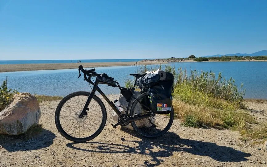 Vélo chargé de sacoches sur un chemin côtier